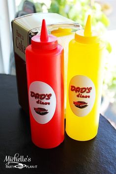 two plastic bottles sitting next to each other on top of a black table with a box in the background