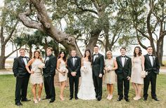 a group of people standing next to each other in front of trees and grass on a field