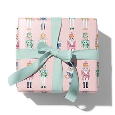 a present wrapped in pink and green wrapping paper with cartoon characters on it, tied to a light blue ribbon