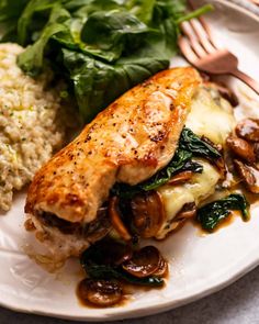 a white plate topped with meat covered in mushrooms and spinach next to broccoli