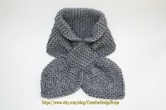 a gray knitted scarf with a hood on the top and bottom, sitting in front of a white background