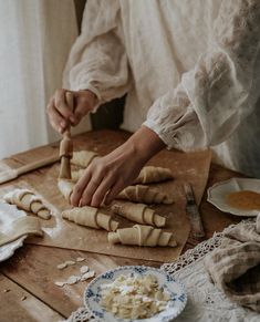 a woman is making bread rolls on a wooden table