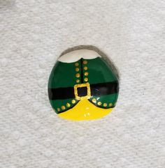 a green and yellow christmas ornament with a gold buckle on it's chest