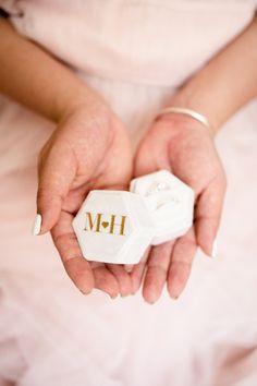 a woman in a pink dress holding a white object with the word m - h on it