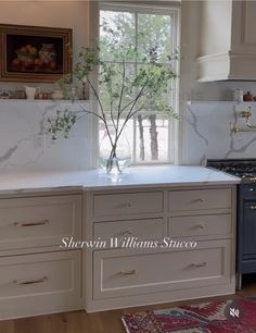 a kitchen with white cabinets and marble counter tops, an oven and sink are in front of the window