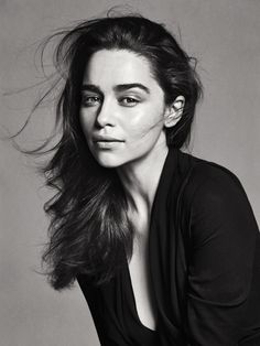 a black and white photo of a woman with her hair blowing in the wind, looking at the camera