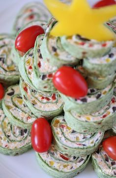 a plate topped with green cupcakes covered in frosting and cherry tomatoes next to a yellow star