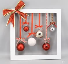 an ornament in a box with red and white ornaments hanging from it's side