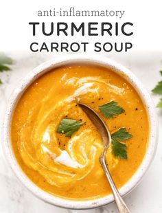 a white bowl filled with carrot soup and garnished with cilantro leaves