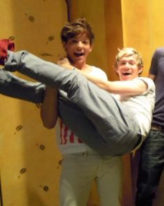 three men are posing for the camera with one man upside down on his leg and another standing behind him