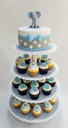 a three tiered cake with cupcakes and an elephant on top