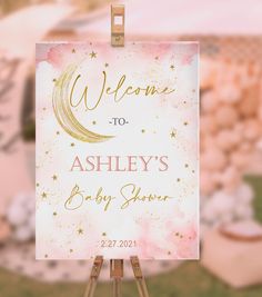 a welcome sign is on an easel in front of a pink and gold background