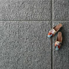 a pair of shoes sitting on top of a gray floor next to a wall covered in carpet