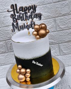 there is a birthday cake that has been decorated with gold and black balls on it