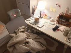 a bed room with a desk and a chair next to a lamp on top of it