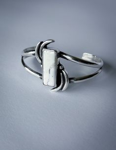 The White Buffalo gemstone, featuring a chic black and white palette, brings a touch of class and timeless elegance to this cuff. Designed with a vibrant movement pattern, the cuff features a deep patina for added depth and a high polish for ultimate shine. Embrace the simplicity and sophistication of winter with this versatile piece that effortlessly complements any look, day or night. MATERIALS White Buffalo Sterling Silver SIZE L Large. 6 inch cuff with a 1 inch gap; wrist circumference 7-7.5 inches Note: The cuff can be sized down to a smaller size for an additional $20 charge. Please contact me here; mention the product name and size! DIMENSIONSCenterpiece 1 and 1/2 inch tall White Polished Cuff Jewelry, Elegant White Gemstone Cuff Bracelet, Modern White Cuff Bracelet, Adjustable White Gemstone Cuff Bracelet, Black And White Palette, Movement Pattern, The White Buffalo, White Palette, White Buffalo