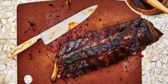 a steak on a cutting board with a knife next to it and sauce in a bowl