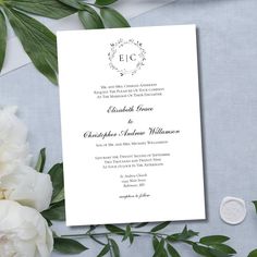 a wedding card with white flowers and greenery