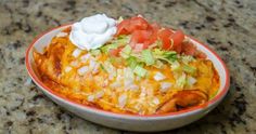 a bowl filled with taco salad on top of a granite counter next to a cup of sour cream