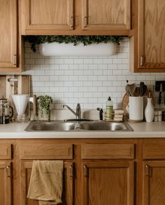 a kitchen with wooden cabinets and white tile backsplash, wood cabinetry, and stainless steel sink