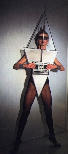 a woman in tights and stockings holding a radio on top of her body with a triangle shaped object hanging from it's side