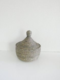 a white and black basket sitting on top of a table next to a wall in the background