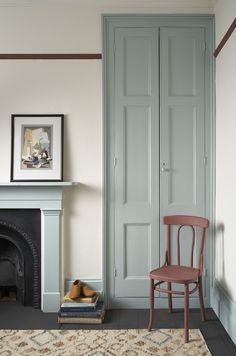 a room with a chair, fireplace and painting on the wall in it's corner