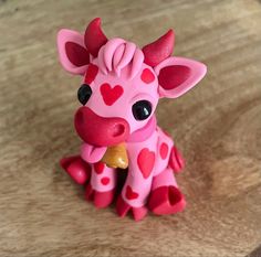 a pink toy giraffe with hearts on it's face sitting on a table