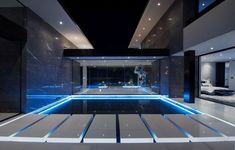 an indoor swimming pool surrounded by white and black walls, with blue lights on the floor