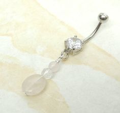 Belly ring features a natural rose quartz gemstone nugget accented with your choice of opalite, ruby or faceted clear quartz. You choose from prong set style barbell with clear crystal gem or standard round surgical steel barbell with clear crystal gem. Belly ring measures 1 7/8 inches long total length. Barbell is 14g surgical steel with a 11mm wearable bar length. For Belly Button Rings: https://www.etsy.com/shop/AllAboutClass?section_id=18474235&ref=shopsection_leftnav_1 For Industrial Ba Rose Quartz Belly Button Ring, Cheap Nickel-free Pink Belly Rings, Nickel-free Silver Dangle Belly Rings, Adjustable Nickel-free Stainless Steel Belly Rings, Nickel-free Dangle Belly Rings In Sterling Silver, Dangle Belly Rings, Rose Quartz Gemstone, Body Piercing Jewelry, Belly Rings