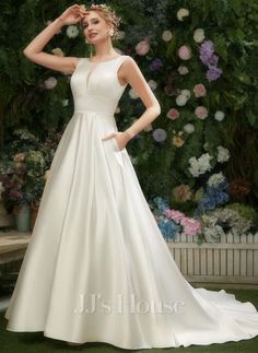 a woman in a white wedding dress standing next to a flower wall with her hand on her head