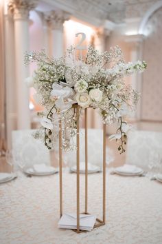 an elegant centerpiece with white flowers and baby's breath is displayed on a table