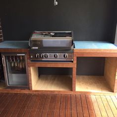 an outdoor bbq and grill on a deck next to a brick wall with a door open