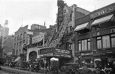 an old black and white photo of cars parked in front of a theater on the street