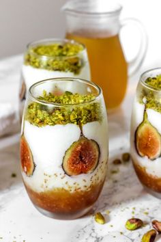 three glasses filled with different kinds of desserts on top of a marble countertop