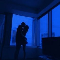 two people standing in front of a window hugging