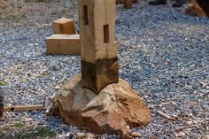 a wooden sculpture sitting on top of a pile of rocks next to a tree stump