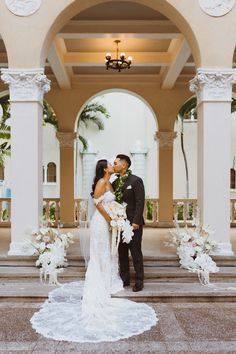 a bride and groom kissing in front of an archway at their wedding ceremony with white flowers