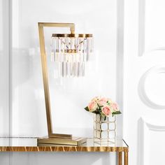 a vase with flowers on a table next to a gold lamp and mirror cubes