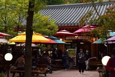 many people are sitting under umbrellas at an outdoor cafe in the city, some with lights on them