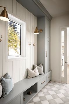 a white and gray entryway with two lamps on either side of the bench, one lamp is gold