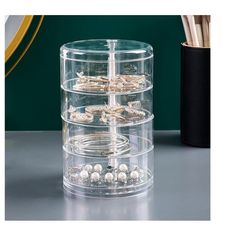 three tiered clear container with beads and pens on the table next to a pen holder