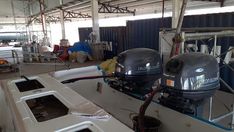 two motor boats are parked in a storage area with other equipment on the ground behind them