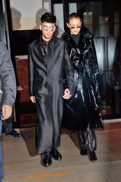 a man and woman dressed in black are walking down the street with their faces painted