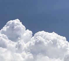 the plane is flying high in the blue sky with white fluffy clouds behind it,