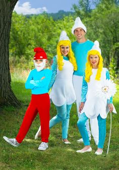 three people dressed in costumes standing next to each other near a tree and grass field