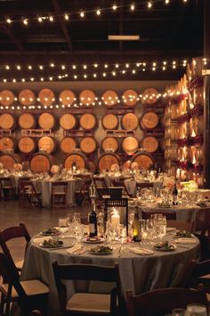 a wine cellar filled with lots of barrels and tables covered in white tablecloths