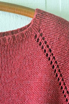 a close up of a red sweater on a wooden chair with white wall in the background