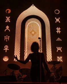 a woman standing in front of a stage with musical symbols projected on the wall behind her