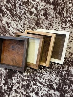 four wooden frames sitting on top of a brown and white animal print surface with one missing